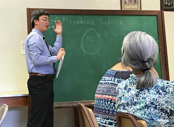 Rev. Tomioka gestures at the blackboard with seated students in the foreground