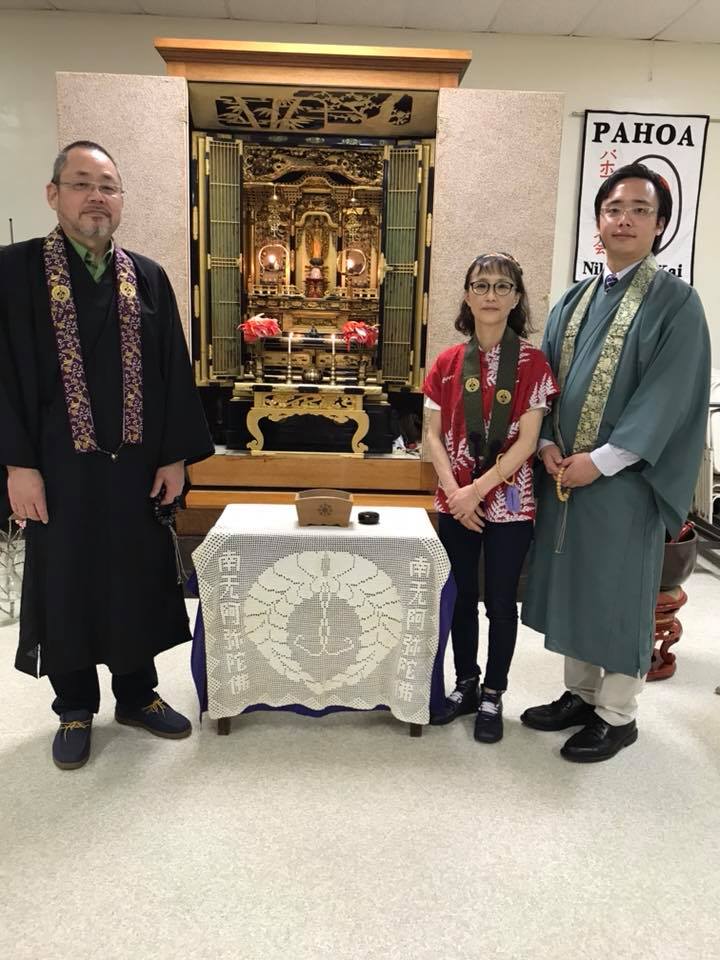 Rev. Tomioka stands with another minister and a woman wearing Monto Shikisho at the altar